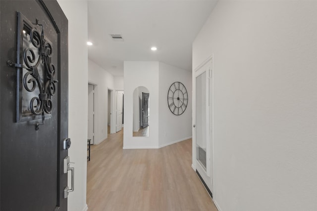 hallway with baseboards, visible vents, arched walkways, light wood-type flooring, and recessed lighting