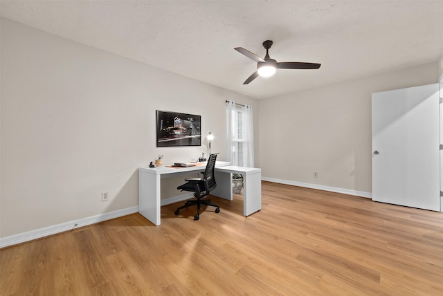 office area with light wood finished floors, a ceiling fan, and baseboards