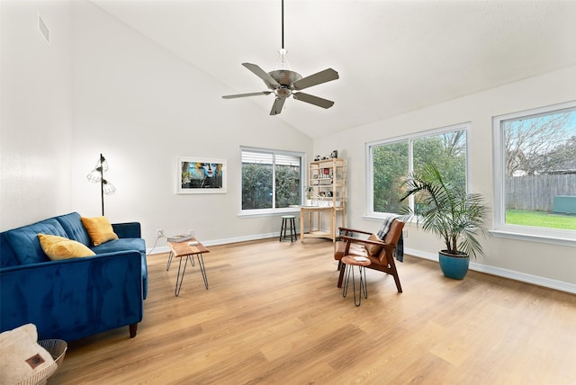 living area featuring vaulted ceiling, light wood-type flooring, a ceiling fan, and baseboards