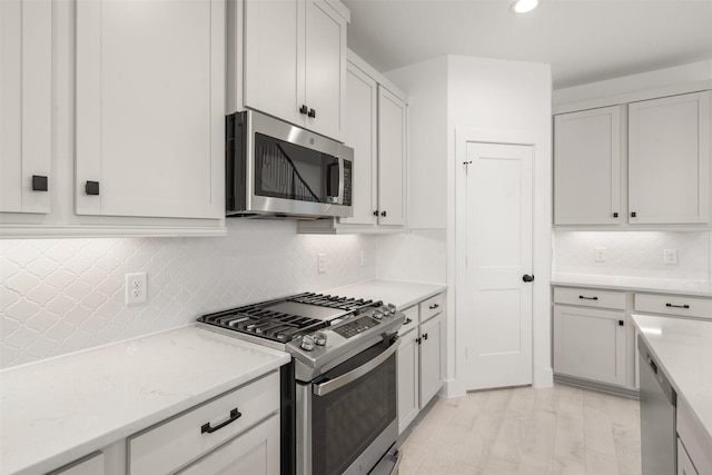 kitchen with recessed lighting, stainless steel appliances, white cabinetry, backsplash, and light wood finished floors