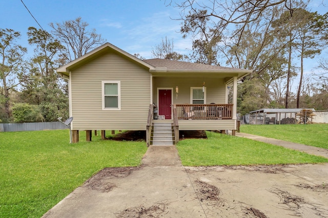 view of front of house with covered porch, a shingled roof, fence, and a front yard