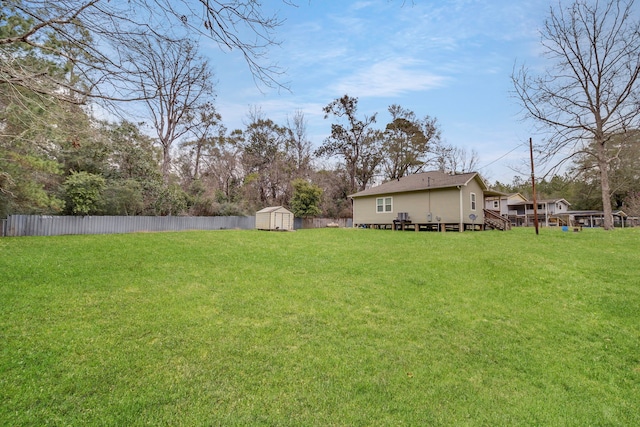 view of yard with an outdoor structure, a deck, fence, and a shed