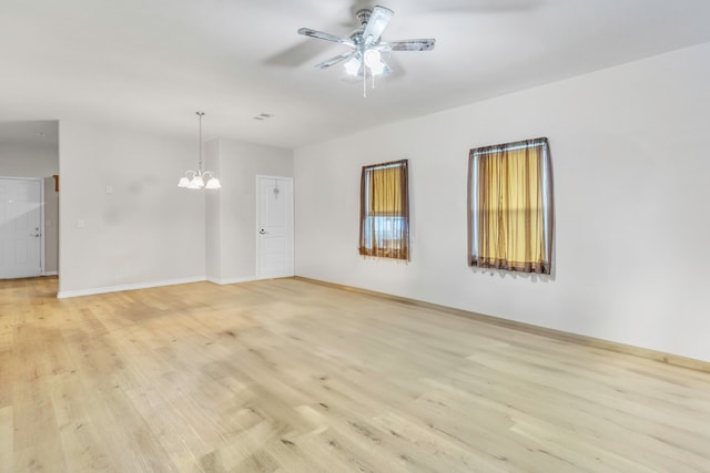 unfurnished room featuring baseboards, ceiling fan with notable chandelier, and light wood finished floors