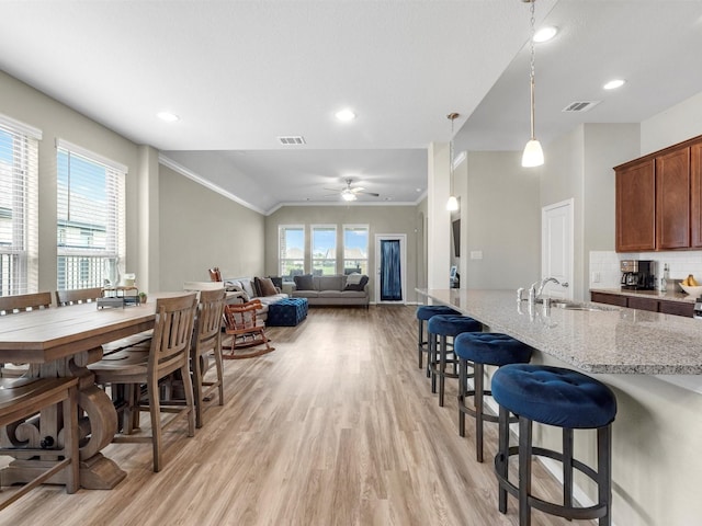 kitchen with pendant lighting, visible vents, open floor plan, a sink, and light stone countertops