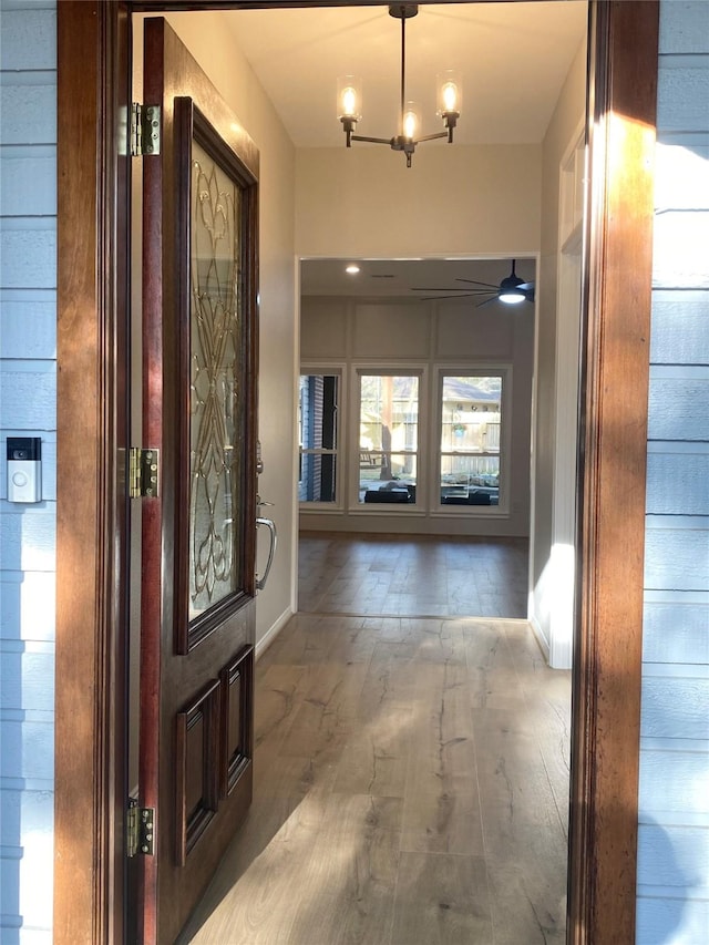 entrance foyer with ceiling fan with notable chandelier and wood finished floors