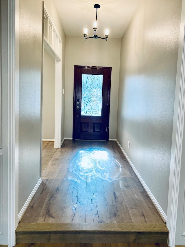 foyer featuring a chandelier, light wood-style flooring, and baseboards