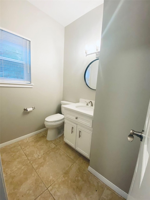 bathroom featuring toilet, tile patterned floors, baseboards, and vanity