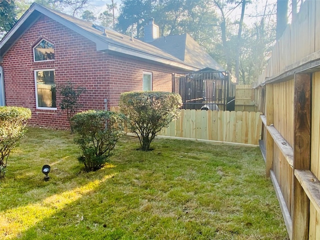 view of side of property with brick siding, a lawn, a chimney, and fence