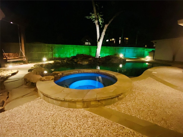 pool at twilight featuring an outdoor pool, a patio, and an in ground hot tub