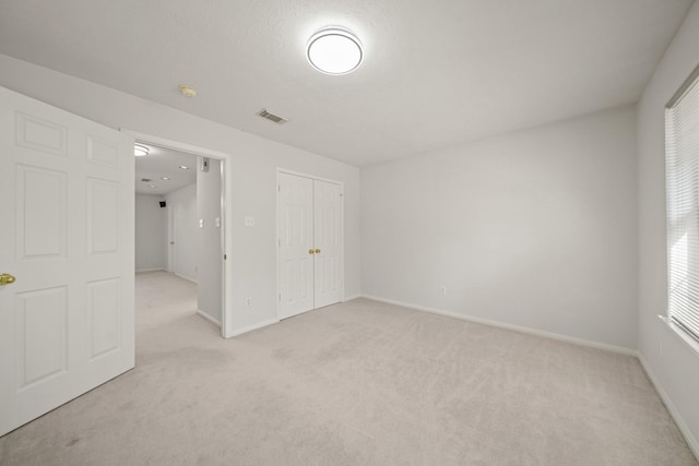 empty room with light colored carpet, visible vents, and baseboards