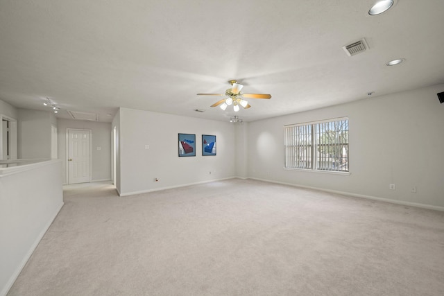 empty room with visible vents, attic access, light carpet, ceiling fan, and baseboards