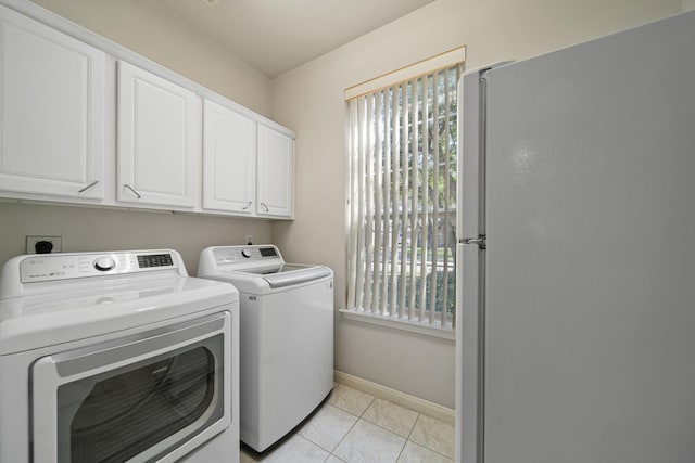 clothes washing area featuring cabinet space, light tile patterned flooring, baseboards, and washing machine and clothes dryer