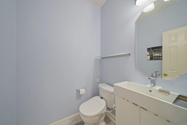 bathroom with baseboards, vanity, and toilet