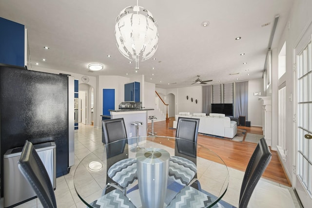 dining room with arched walkways, light tile patterned floors, stairway, and recessed lighting