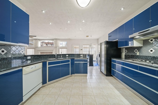 kitchen featuring dishwasher, decorative light fixtures, blue cabinetry, under cabinet range hood, and a sink