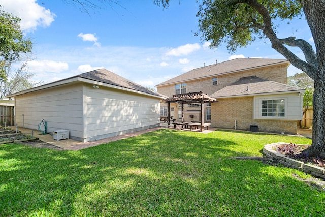 back of house with brick siding, fence, a pergola, and a yard