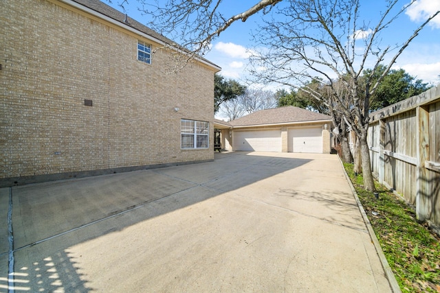 view of side of home with concrete driveway, brick siding, and fence