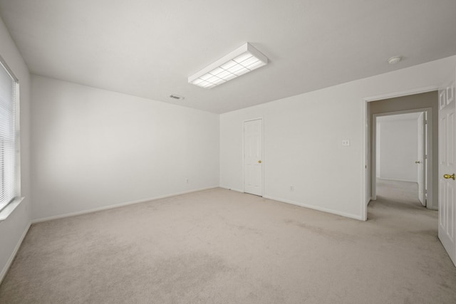 unfurnished room with light colored carpet and baseboards