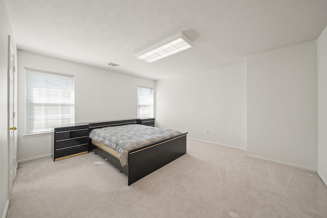 bedroom with light colored carpet, visible vents, baseboards, and a textured ceiling