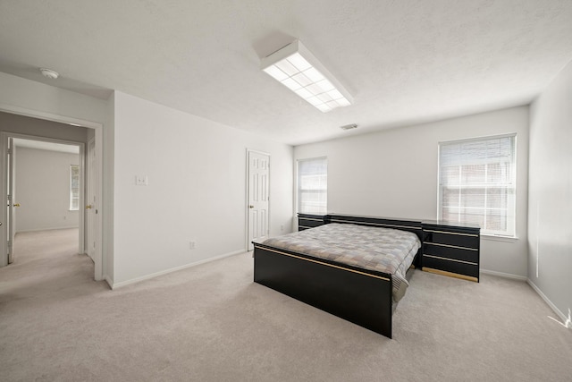 bedroom with baseboards, visible vents, and light colored carpet