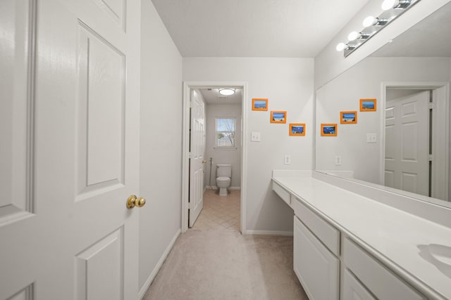 bathroom with toilet, vanity, and baseboards