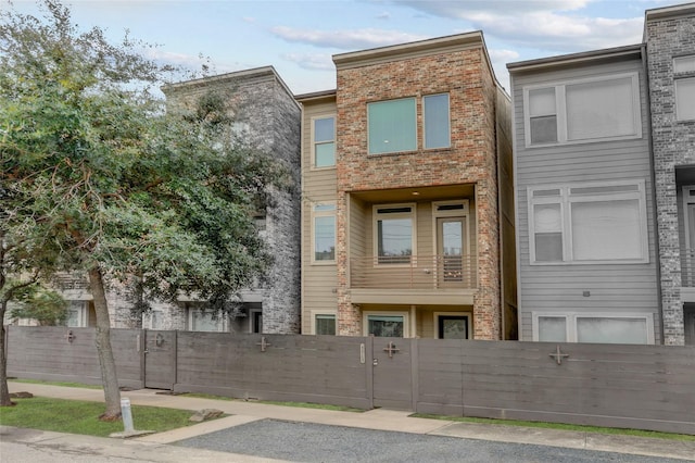 view of property featuring brick siding, a fenced front yard, and a gate