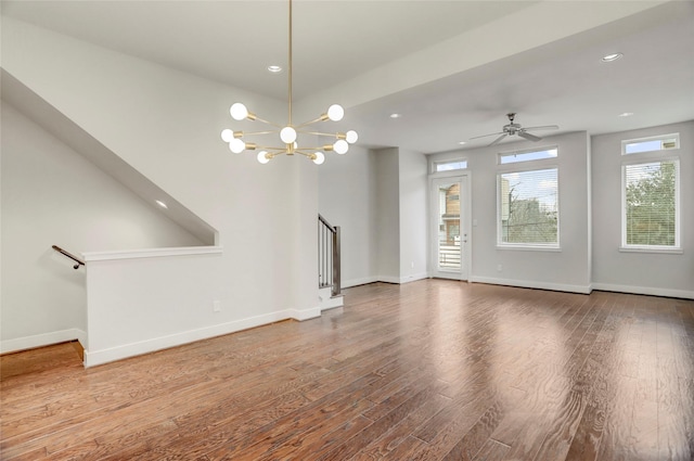 unfurnished living room featuring baseboards, stairway, and wood finished floors