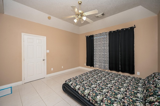 bedroom with light tile patterned floors, baseboards, visible vents, lofted ceiling, and a textured ceiling