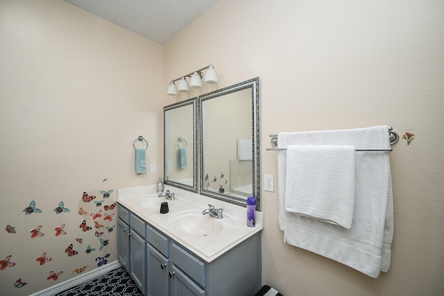 bathroom with a sink, baseboards, and double vanity