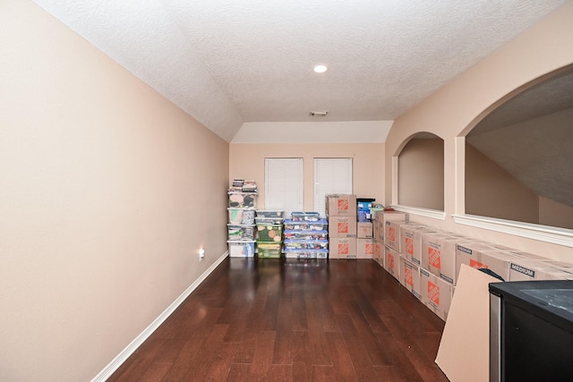 corridor with a textured ceiling, dark wood-style flooring, visible vents, and baseboards