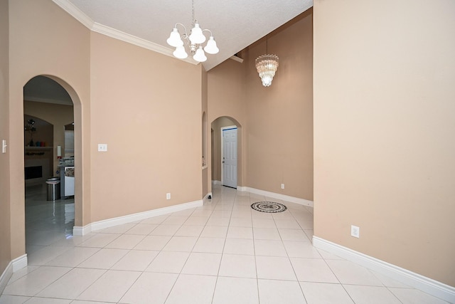 empty room with ornamental molding, arched walkways, a notable chandelier, and light tile patterned floors