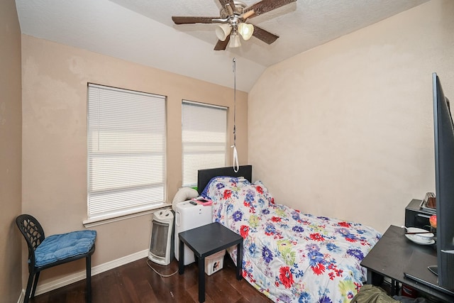 bedroom featuring dark wood-type flooring, vaulted ceiling, baseboards, and a ceiling fan