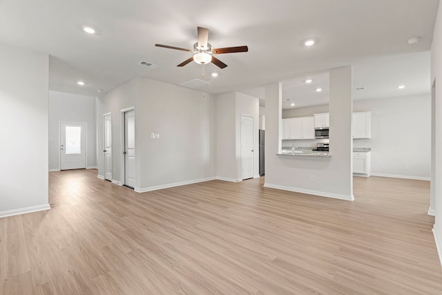 unfurnished living room with recessed lighting, visible vents, ceiling fan, light wood-type flooring, and baseboards