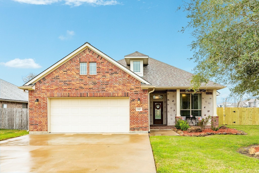 view of front of house featuring brick siding, an attached garage, a front yard, fence, and driveway