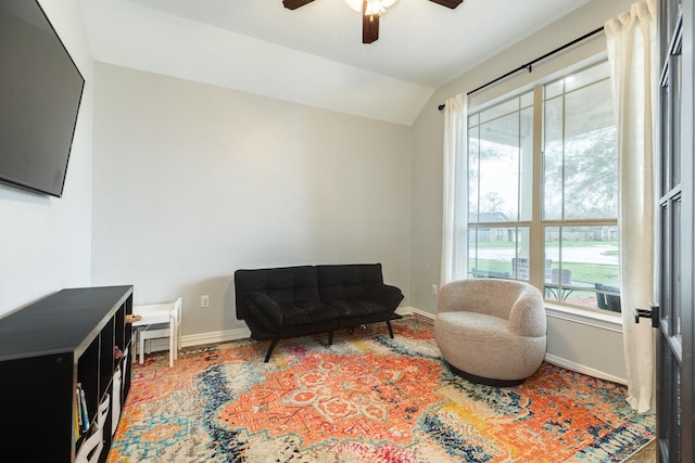 living area with vaulted ceiling, a ceiling fan, and baseboards