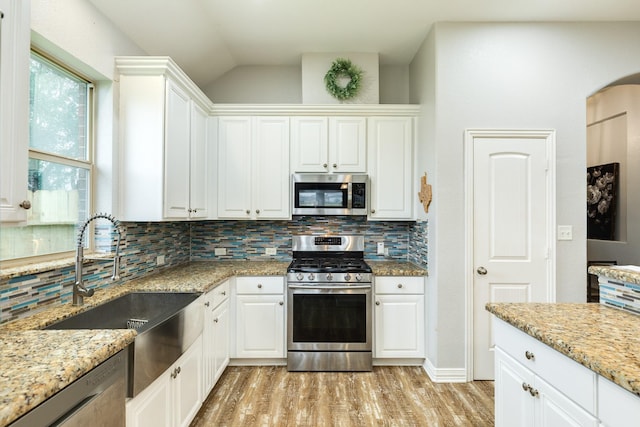 kitchen featuring light wood-style floors, white cabinetry, stainless steel appliances, and backsplash