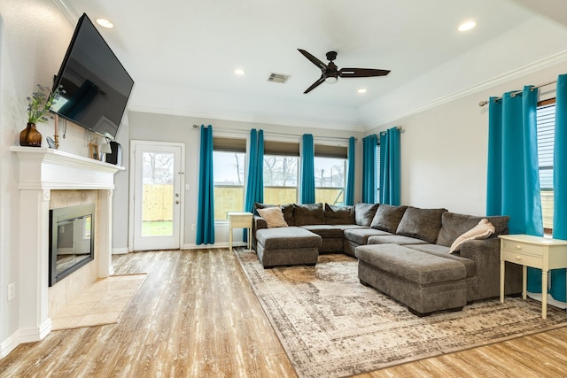 living area with crown molding, a fireplace, visible vents, and wood finished floors