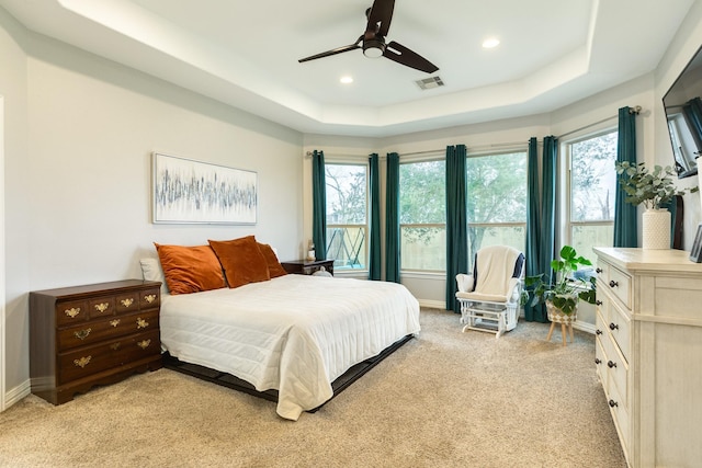 bedroom with recessed lighting, light carpet, visible vents, baseboards, and a tray ceiling