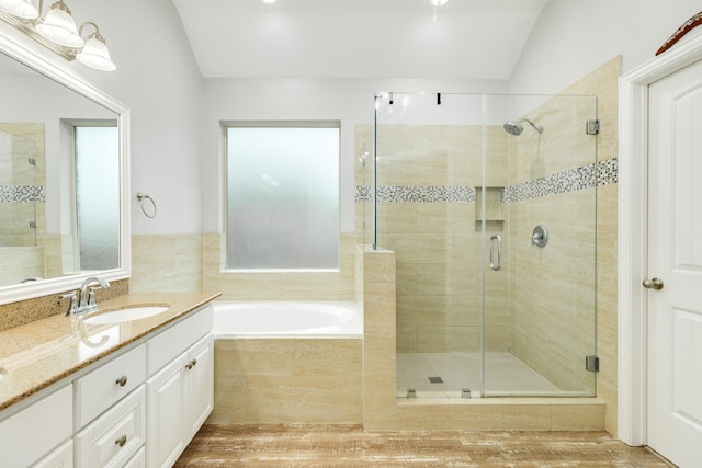 full bathroom featuring a garden tub, a stall shower, vaulted ceiling, vanity, and wood finished floors