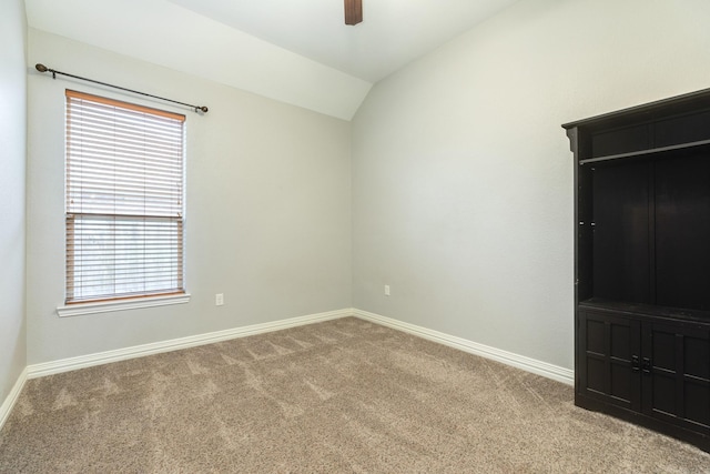 unfurnished bedroom with light carpet, ceiling fan, baseboards, and lofted ceiling