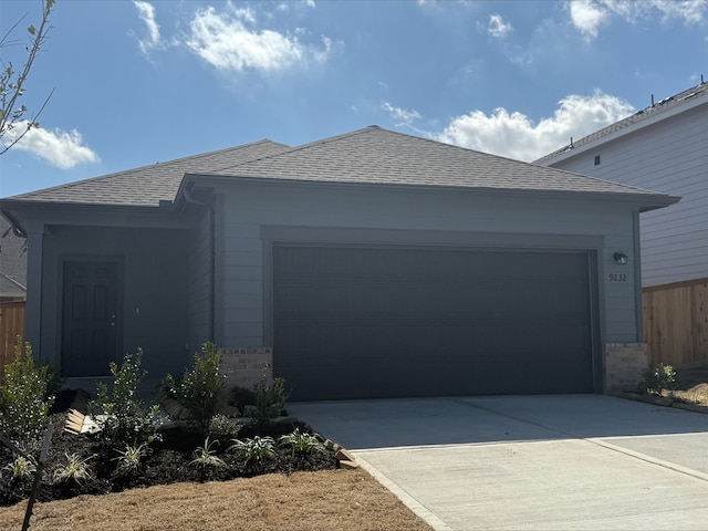 view of front of house with an attached garage, driveway, a shingled roof, and brick siding