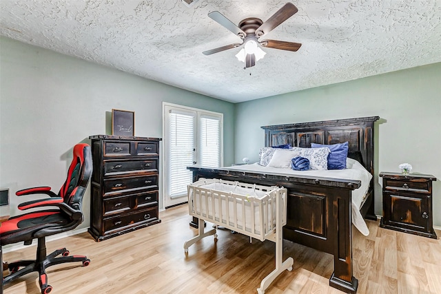 bedroom with light wood-type flooring, ceiling fan, and a textured ceiling