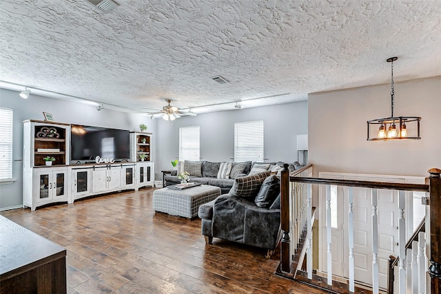 living room featuring a textured ceiling, ceiling fan, dark wood finished floors, and rail lighting