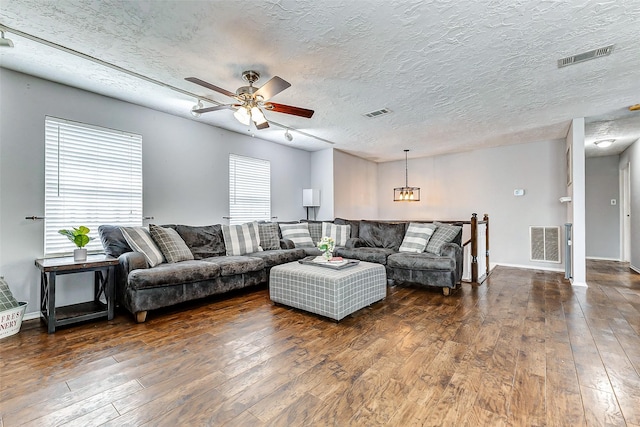 living room with a textured ceiling, dark wood finished floors, and visible vents