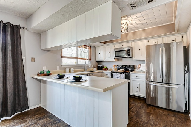 kitchen with visible vents, appliances with stainless steel finishes, a peninsula, light countertops, and white cabinetry