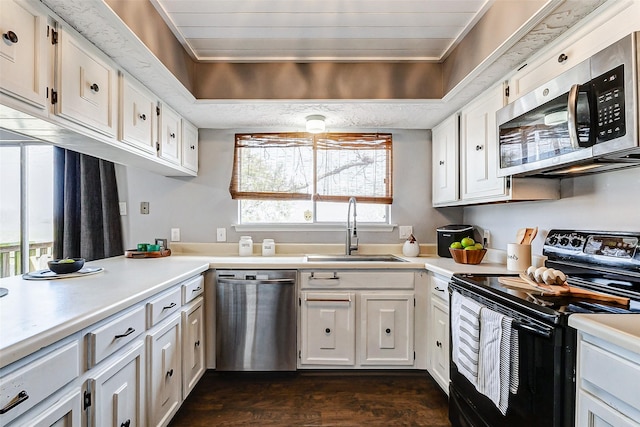 kitchen featuring stainless steel appliances, dark wood-style flooring, a sink, white cabinets, and light countertops