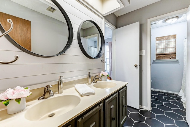 full bath featuring double vanity, tile patterned flooring, a sink, and visible vents