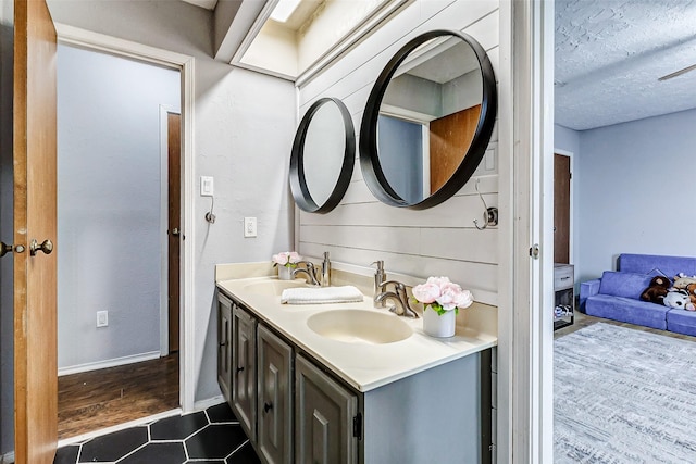 bathroom with double vanity, tile patterned flooring, a textured ceiling, and a sink