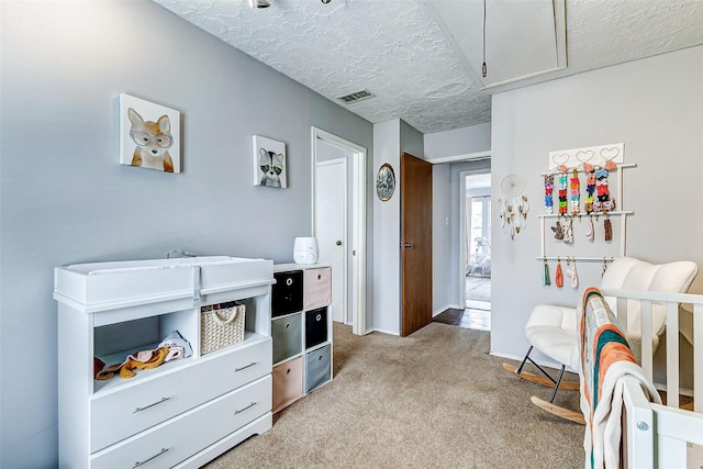 bedroom featuring a textured ceiling, light carpet, visible vents, baseboards, and attic access