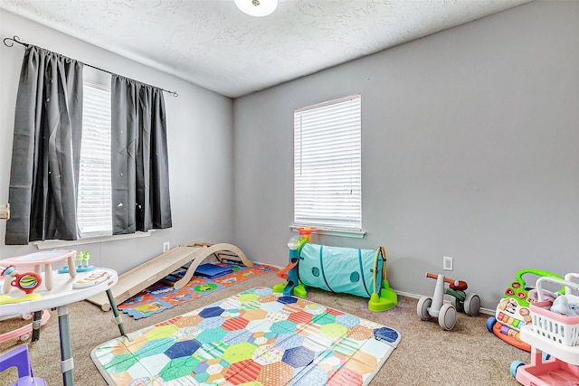 recreation room featuring carpet flooring, a textured ceiling, and baseboards